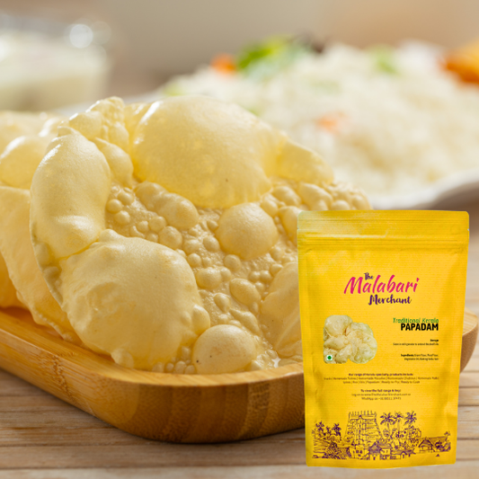 Papadam on a wooden plate with a yellow packaging of 'The Malabari Merchant' in the foreground.
